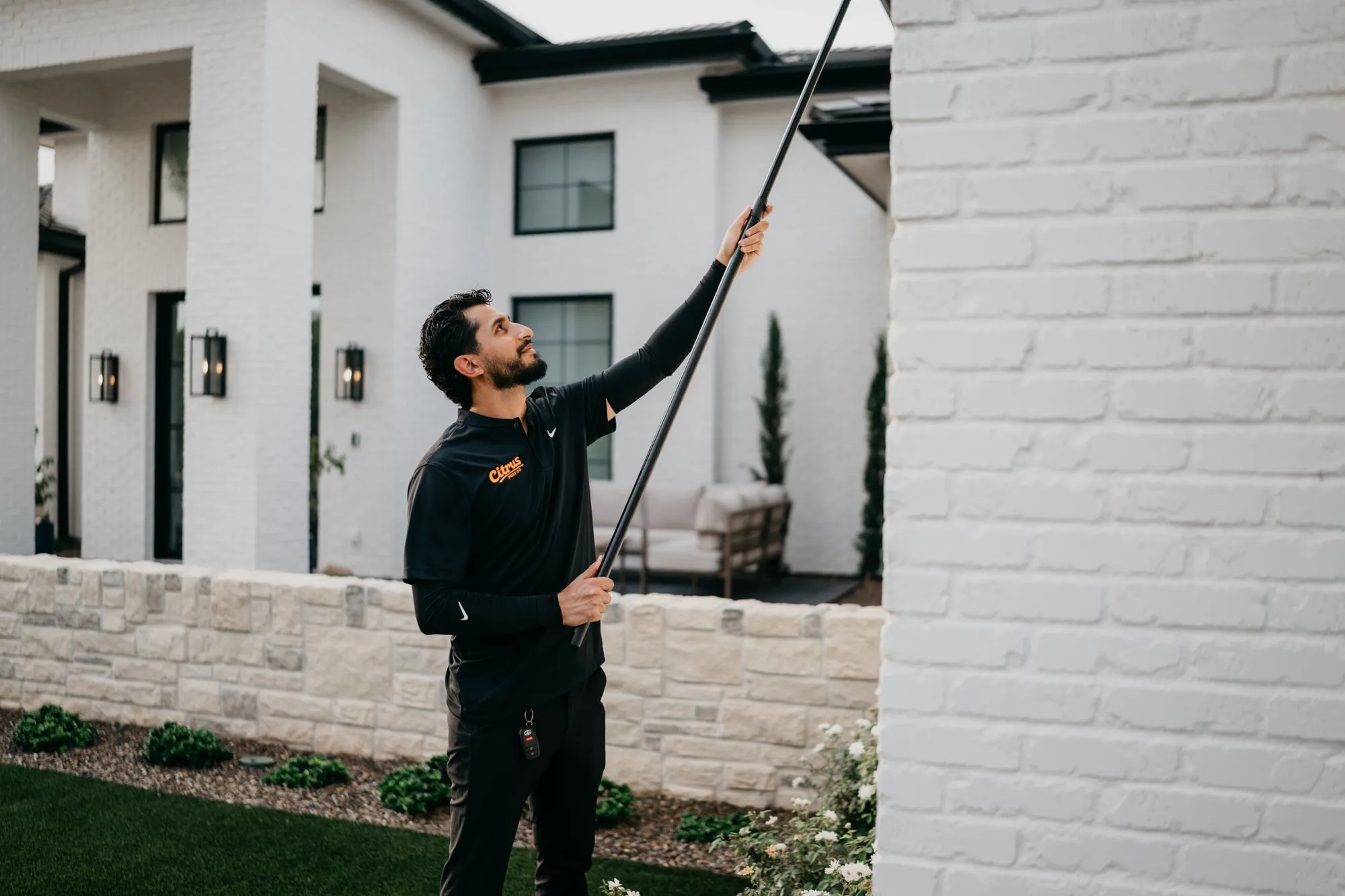Citrus Pest Co technician de-webbing the eaves of an East Valley home with an extension pole