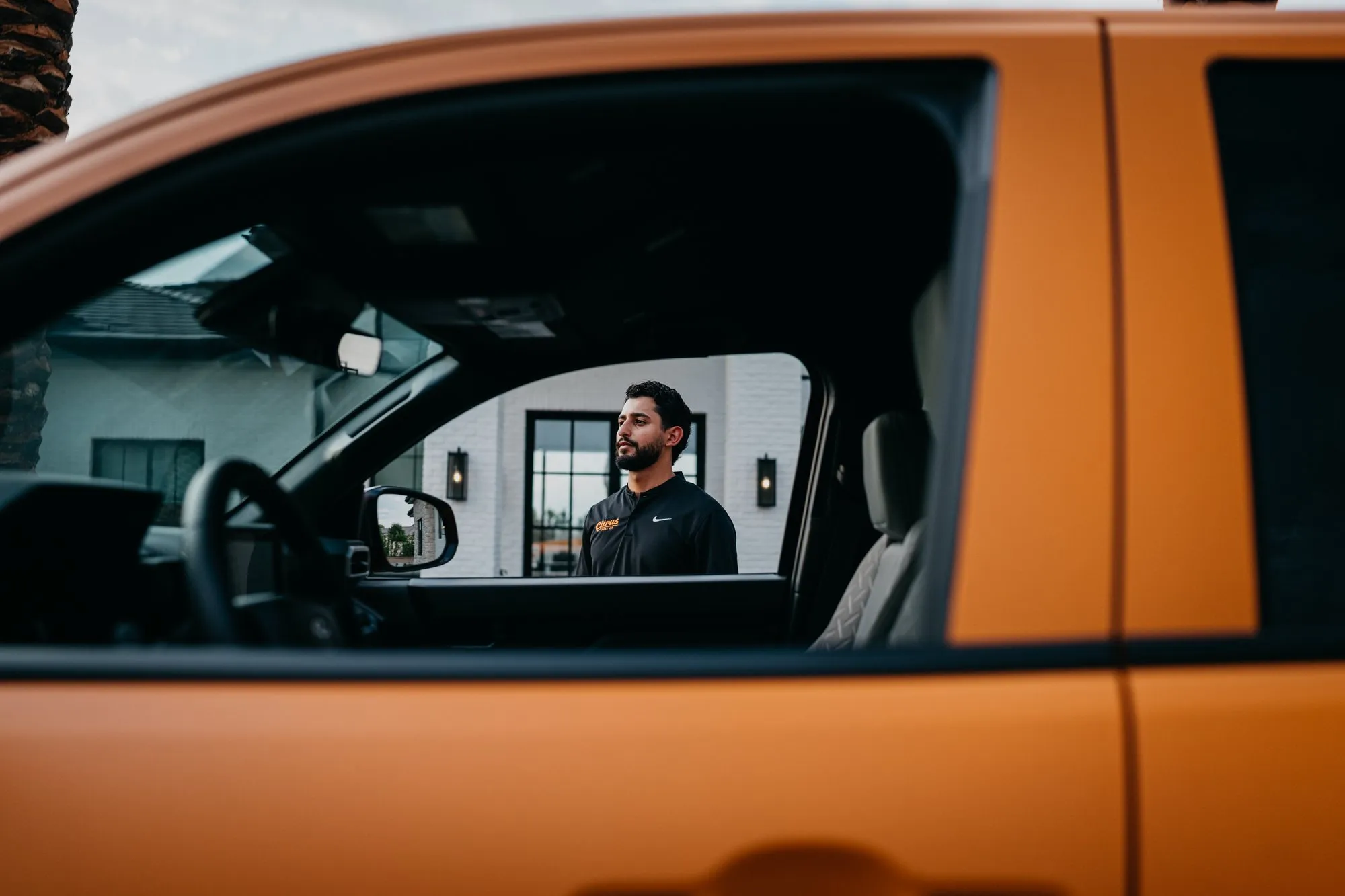 Citrus Pest Co owner beside the orange service truck, seen through the open driver's window