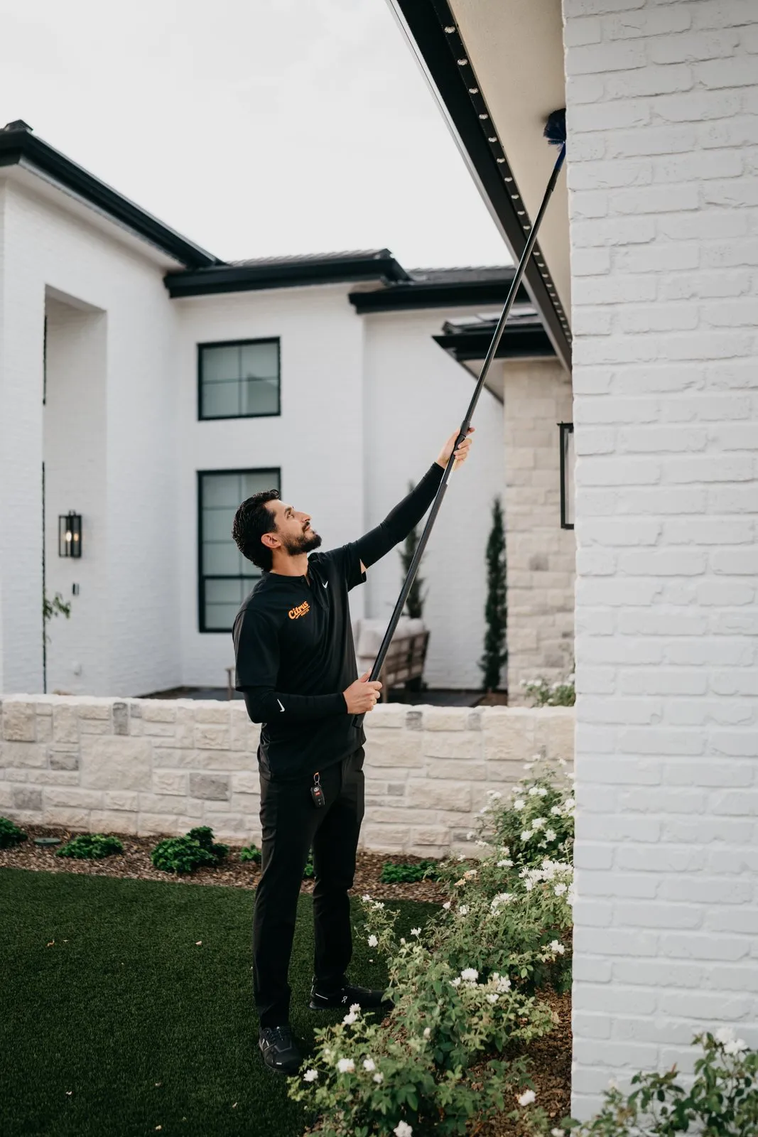 Citrus Pest Co technician de-webbing a home's eaves with an extension pole