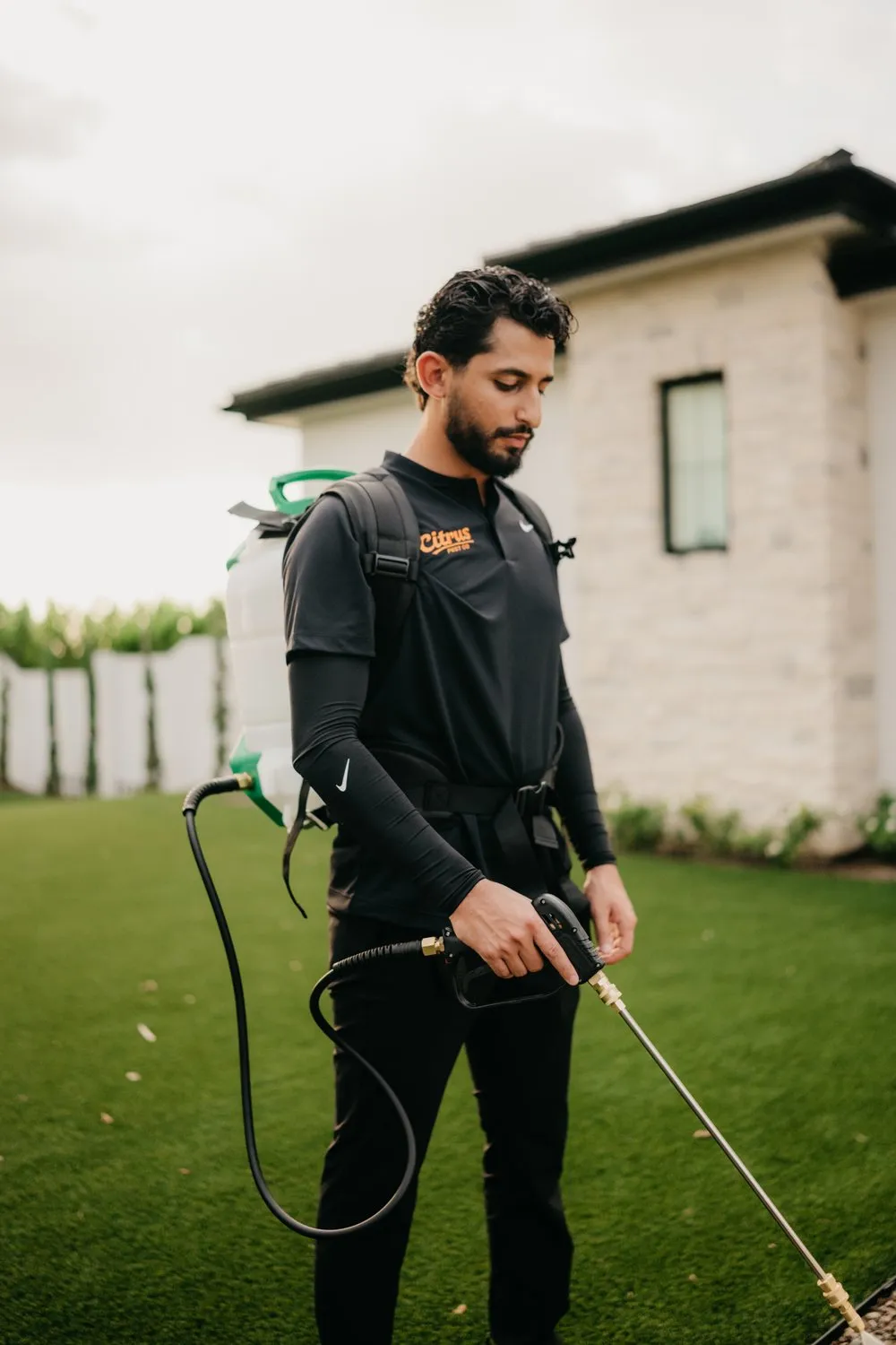 Citrus Pest Co technician treating a home with a backpack sprayer
